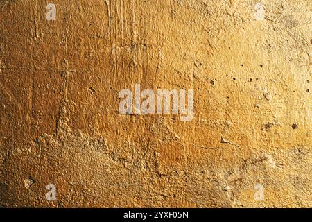 Old worn gold colored wall as grunge texture and background Stock Photo