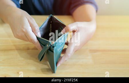 Empty wallet (no money) in the hands of woman over wooden table. Cost control expenses poverty in concept. Selective focus, copy space. Stock Photo
