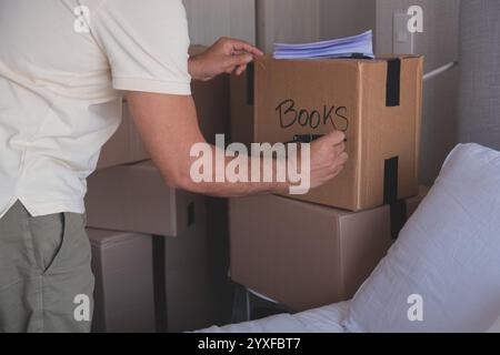 A man is packing boxes and writing books on them. New home concept. Stock Photo