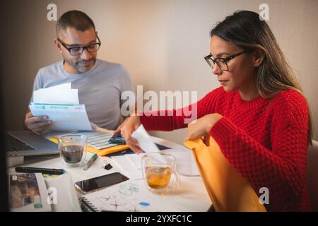 A man and a woman are sitting at a table with papers and a laptop, couple organizing credit documents .New home concept. Stock Photo