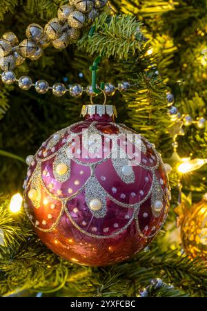 A red and gold coloured bauble decorating a Christmas tree Stock Photo