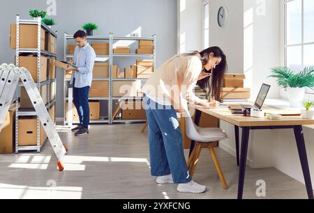 Woman working in warehouse checking stock and inventory with male coworker. Stock Photo
