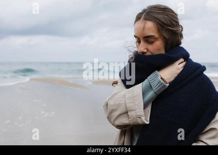 Close-up of a woman bundled up against the cold by the ocean Stock Photo