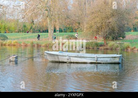 Exploring Bois de Vincennes at dusk with serene waters and leisurely walkers in Paris Stock Photo