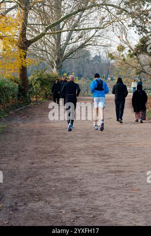 People jogging and walking along a path in Bois de Vincennes park during a cool autumn day in Paris Stock Photo