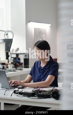 Portrait of Smiling Asian Woman Using Laptop in Modern Office Stock Photo