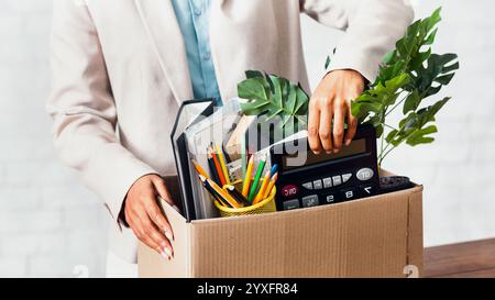 Leaving work concept. Closeup of African American woman with cardboard box of stuff at office Stock Photo