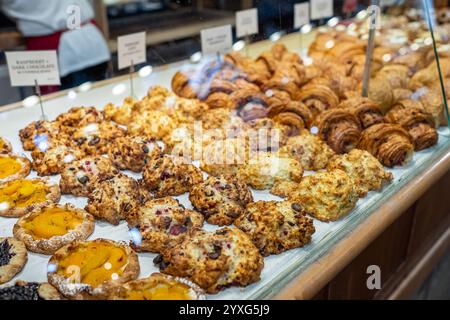 Showcase with different tasty desserts in bakery shop, closeup. Various types of bread and pastry, croissants, cookies on display in a bakery . Modern Stock Photo