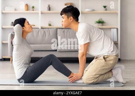 Motivated asian man and woman working on abs at home Stock Photo