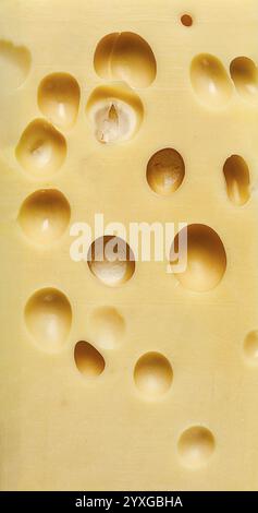 This cheddar cheese block showcases its unique holes and smooth surface, revealing rich yellow tones and creamy texture that invite tasting and enjoym Stock Photo