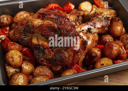 Pork knuckle, baked with vegetables, new potatoes, on a baking sheet, homemade, no people Stock Photo