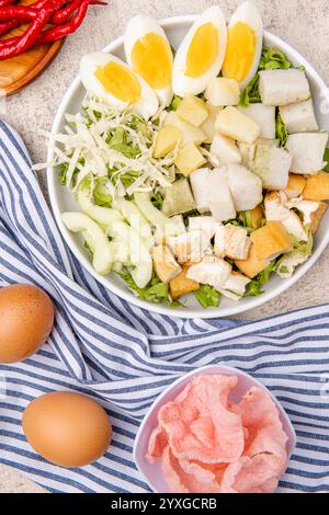 Gado Gado is an Indonesian salad of slightly boiled, blanched or steamed vegetables and hard-boiled eggs, boiled potato, fried tofu and tempeh, and lo Stock Photo