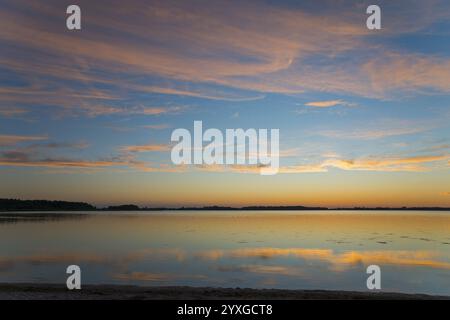 Peaceful sunrise over a smooth lake with pastel-coloured sky and reflections, sunset, Zatoka Wrzosowska, Lake Fritzow, Dziwnow, Zachodniopomorskie, We Stock Photo