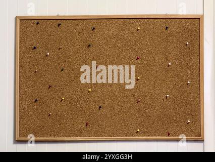 Cork bulletin board with various colored push pins on a wall Stock Photo