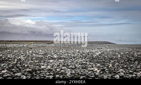 Power lines crossing a vast rocky plain in iceland under cloudy sky Stock Photo