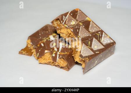 Trend Dubai chocolate bar with peanut butter, sticky caramel and kataifi dough filling on white background. Confectionery and sweets. Stock Photo