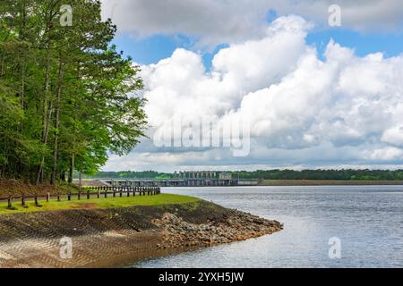 A view of the West Point Lake Dam under a clear blue sky with large white clouds as seen from Eagleview Park in Georgia. Stock Photo