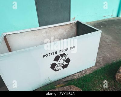 White rectangular collection bin labeled "BOTTLE DROP OFF" with recycling symbol featuring water bottle design, showing dedicated container for plasti Stock Photo