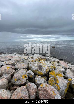 Dramatic coastline with big stones in the foreground and the ocean and cloudy skies in the backgrund. Picture taken in Skåne, Sweden in August 2023. Stock Photo