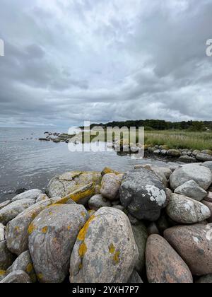 Dramatic coastline with big stones in the foreground and the ocean and cloudy skies in the backgrund. Picture taken in Skåne, Sweden in August 2023. Stock Photo
