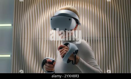 Futuristic neon studio woman explore AR gadget high-tech wear VR glasses goggles gaming simulation helmet female girl play virtual augmented reality Stock Photo