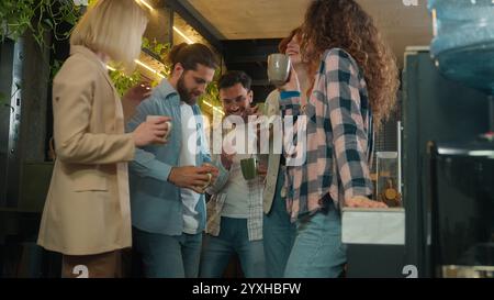 Diverse men women freelancers coworkers dancers friends happy joyful girls guys male female dance music business team office colleagues dancing in bar Stock Photo