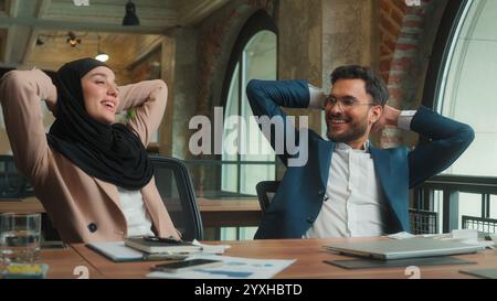 Businessman businesswoman male female working laptop writing notes at office two business colleagues Muslim woman in hijab Indian man finish complete Stock Photo