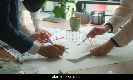 Team architects engineers designers contractors teamwork blueprints building plan on desk paperwork diverse Muslim women Indian man business working Stock Photo