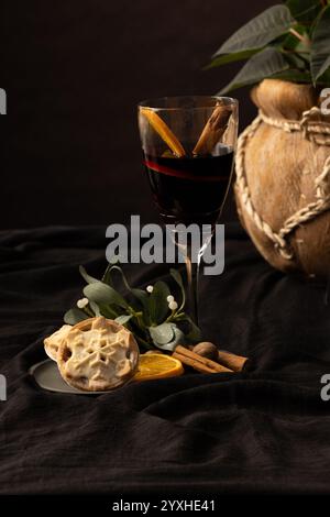 A dark studio background is the foil for rich natural tones of a plate of minced pies with fruit and spices, a plant in a banana leaf pot is in the ba Stock Photo