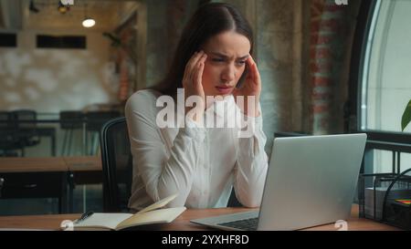 Caucasian businesswoman business woman female lady office worker student studying online work laptop feel headache suffer migraine health problem Stock Photo