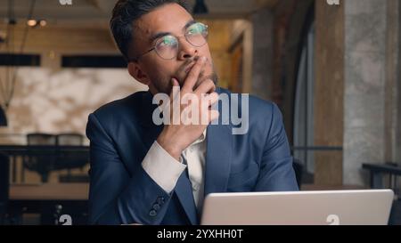 Thoughtful puzzled businessman Arabian Indian man thinking male guy employer worker think idea business plan strategy ponder consider doubt choose Stock Photo