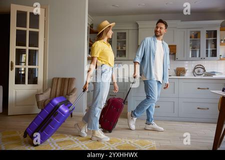 Happy loving couple leaving home with luggage ready for vacation Stock Photo