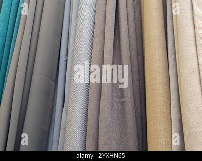 Selection of different colored curtains displayed in a store, various bright fabric textures and materials in neutral tones, home decor curtain option Stock Photo