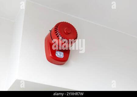 Red fire alarm system speaker buzzer installed on white wall indoors, close-up of emergency alert device, safety equipment in building, no people, fir Stock Photo
