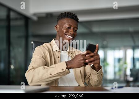Happy smiling Black business man employee using smartphone at work. Stock Photo