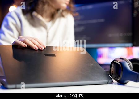 Technician doing software debugging using laptop, checking errors in lines of code displayed on computer monitors. Woman working from home fixing coding mistakes using notebook device Stock Photo