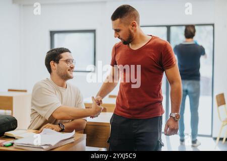Two students shaking hands in a bright classroom setting Stock Photo