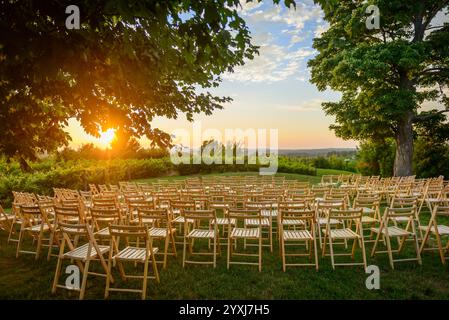 Rows of wood folding chairs set up for outdoor event at sunset Stock Photo