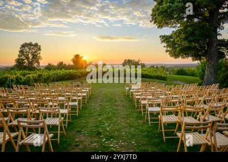 Rows of wood folding chairs set up for outdoor event at sunset Stock Photo