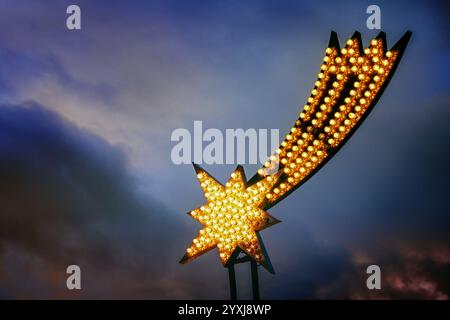 Light installation in the shape of the star of Bethlehem as Christmas decoration against a dark stormy sky, religious symbol in Christianity, copy spa Stock Photo