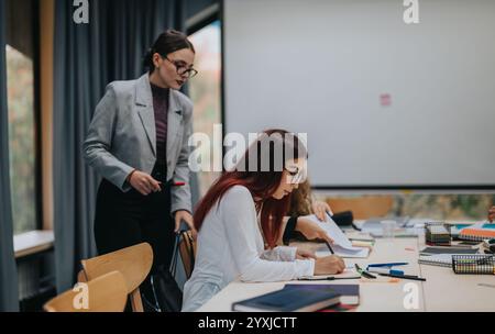 Teacher assisting student with notes in modern classroom setting Stock Photo
