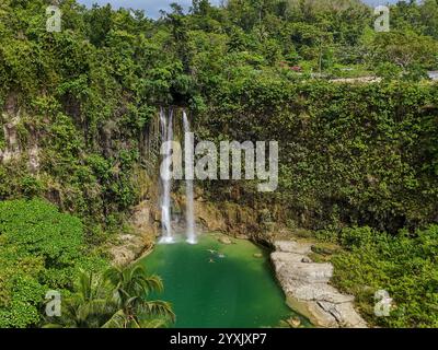 An awe-inspiring tropical waterfall cascading into a vibrant turquoise lagoon, surrounded by lush greenery and cliffs. Ideal for themes of natural bea Stock Photo