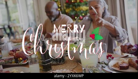 Image of merry christmas text over diverse senior friends at christmas dinner at home. Chirstmas, celebration and tradition concept digitally generate Stock Photo
