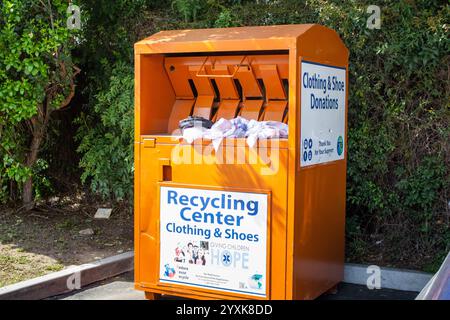 Orange, California, United States - 04-03-2019: A view of an orange public donation bin for clothing and shoes, in a parking lot. Stock Photo