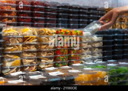 Customer is taking a box of dried fruits from a shelf in a grocery store. The shelves are full of colorful dried fruits Stock Photo