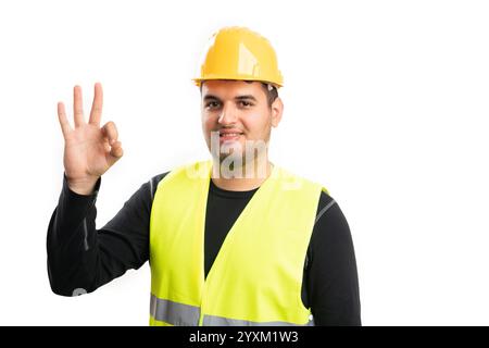Adult male builder wearing fluorescent vest and hardhat smiling showing okay gesture with fingers isolated on white studio background Stock Photo