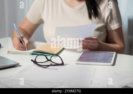 Female paying bills at home. Woman holding invoice in hands and calculates amount of debt. Bill payment online concept. Stock Photo