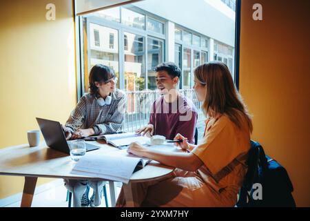 A group of young students embracing city life as they study together in a vibrant cafe, discussing and collaborating on their assignments. Stock Photo