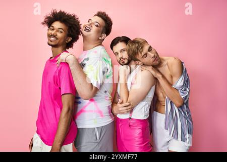 Four individuals express joy and pride in their vibrant outfits against a bright pink background. Stock Photo