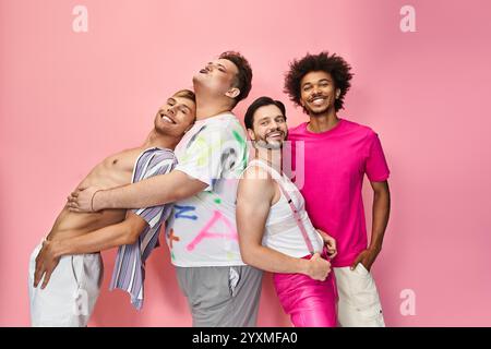 Four individuals express joy and solidarity in colorful attire against a bright pink backdrop. Stock Photo
